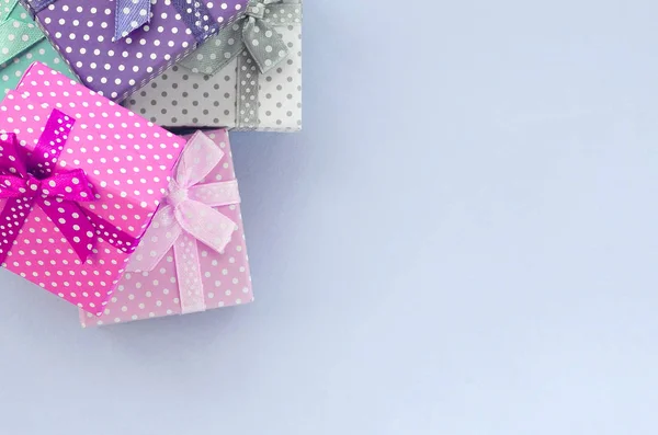 Montón de pequeñas cajas de regalo de colores con cintas se encuentra sobre un fondo violeta —  Fotos de Stock
