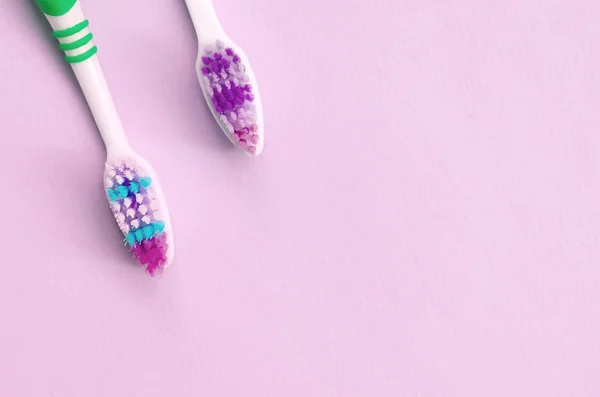 Two toothbrushes lie on a pastel pink background — Stock Photo, Image
