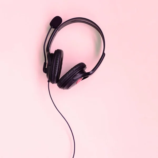 Концепция прослушивания музыки. Черные наушники лежат на розовом фоне — стоковое фото