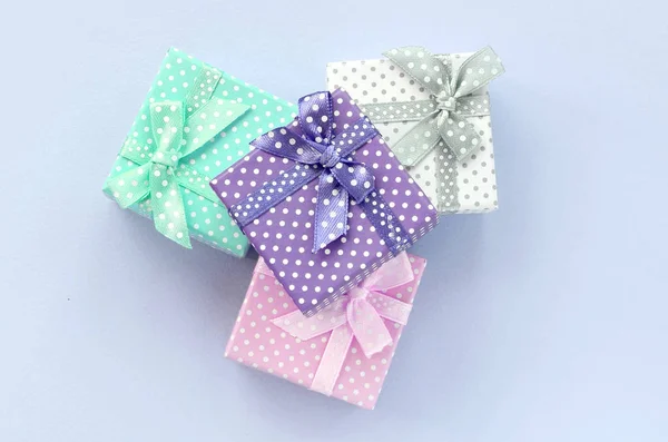 Stapel einer kleinen farbigen Geschenkschachtel mit Schleifen liegt auf violettem Hintergrund — Stockfoto