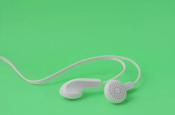 Um modelo para os fãs de música. Fones de ouvido brancos no verde — Fotografia de Stock