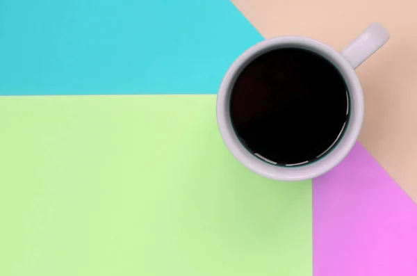 Pequeña taza de café blanco en el fondo de textura de la moda pastel rosa, azul, coral y papel de colores de cal — Foto de Stock