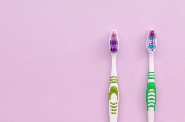Twee tandenborstels liggen op een pastel roze achtergrond — Stockfoto