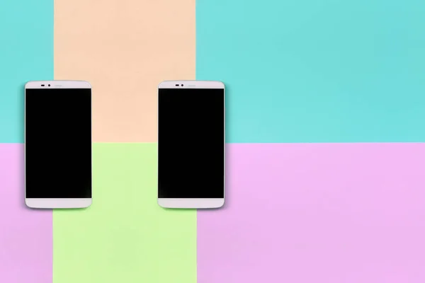 Dos smartphones modernos con pantallas negras sobre fondo de colores pastel de moda rosa, azul, coral y lima — Foto de Stock