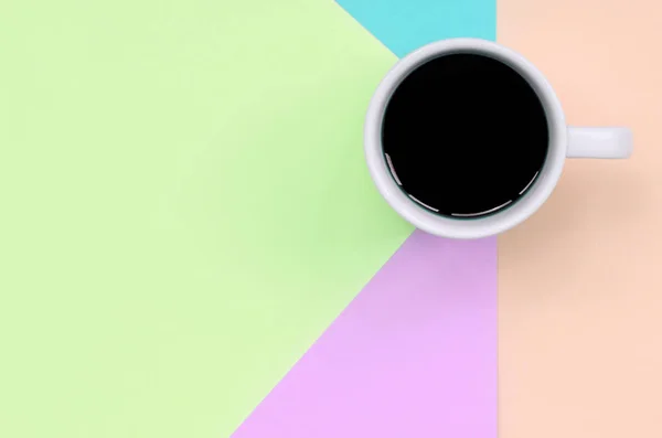 Pequeña taza de café blanco en el fondo de textura de la moda pastel rosa, azul, coral y papel de colores de cal — Foto de Stock