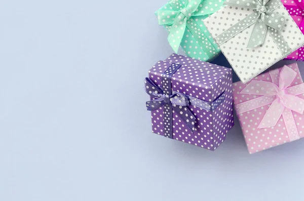 Halom egy kis színes ajándékdoboz szalagok fekszik a lila háttér — Stock Fotó