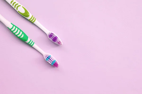 Two toothbrushes lie on a pastel pink background — Stock Photo, Image