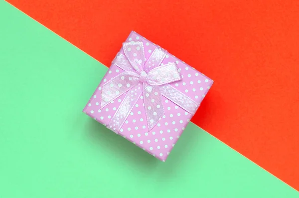 Kleine rosa Geschenkbox liegen auf Textur Hintergrund der Mode Pastell Türkis und roten Farben Papier — Stockfoto