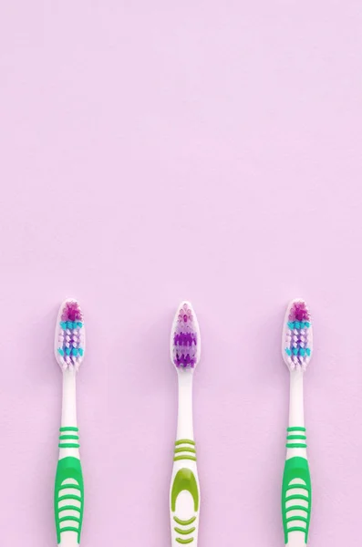 Muitas escovas de dentes estão em um fundo rosa pastel — Fotografia de Stock