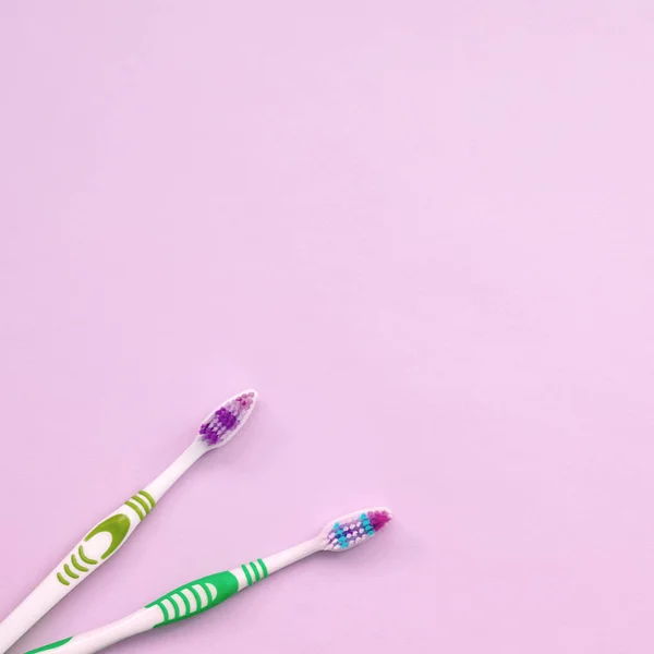 Dwie szczoteczki do zębów leżą na pastelowych różowym tle — Zdjęcie stockowe