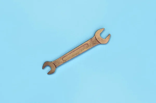 Металлический гаечный ключ лежит на текстурном фоне бумаги пастельно-голубого цвета — стоковое фото