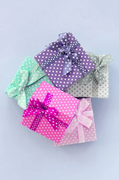 Stapel einer kleinen farbigen Geschenkschachtel mit Schleifen liegt auf violettem Hintergrund — Stockfoto