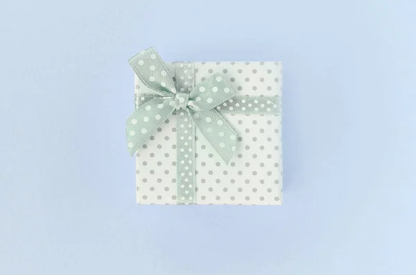 Мала біла подарункова коробка зі стрічкою лежить на фіолетовому фоні — стокове фото