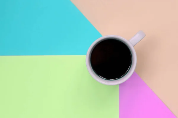 Pequeña taza de café blanco en el fondo de textura de la moda pastel rosa, azul, coral y papel de colores de cal — Foto de Stock