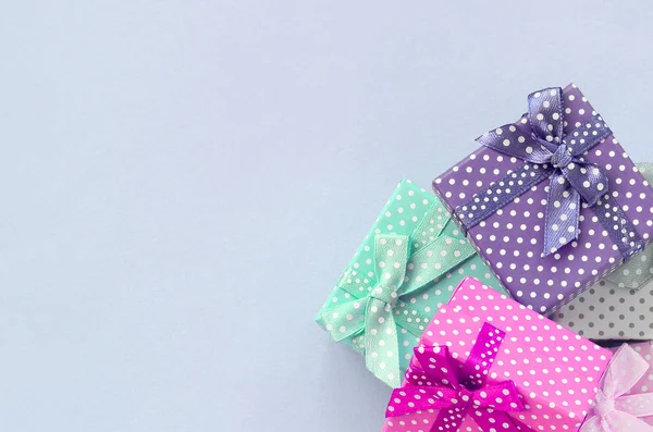 Montón de pequeñas cajas de regalo de colores con cintas se encuentra sobre un fondo violeta —  Fotos de Stock