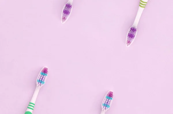 A lot of toothbrushes lie on a pastel pink background — Stock Photo, Image