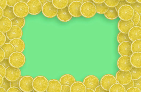 Рамка из желтого лимона цитрусовых ломтиков на ярком фоне лайма — стоковое фото