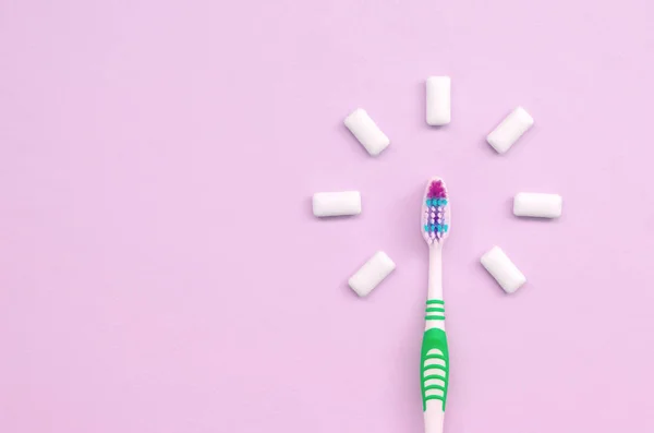 Toothbrush and chewing gums lie on a pastel pink background — Stock Photo, Image