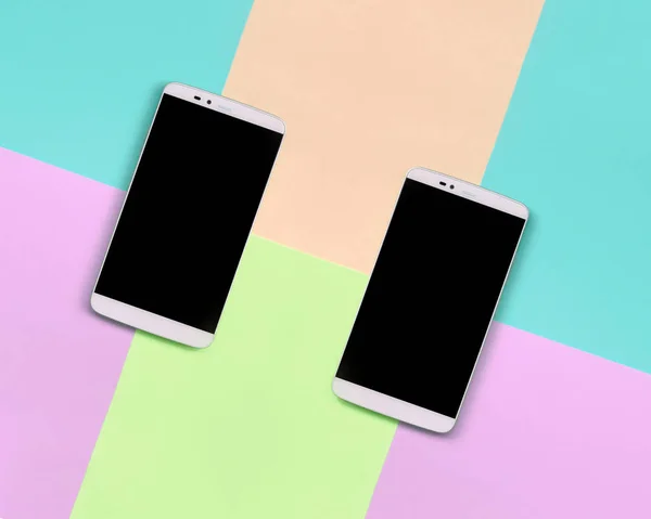 Dos smartphones modernos con pantallas negras sobre fondo de colores pastel de moda rosa, azul, coral y lima — Foto de Stock