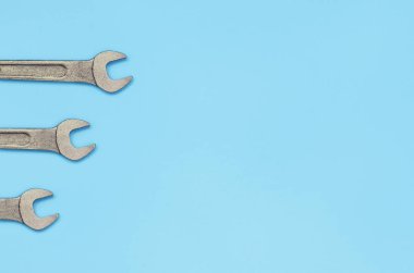 Üç metalik spanners moda pastel mavi renkli kağıt doku arka plan üzerinde yalan