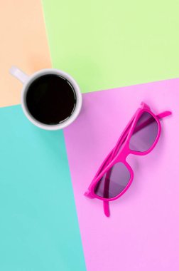 Moda pastel pembe, mavi, mercan ve kireç renkleri arka planda küçük beyaz kahve fincanı ve pembe güneş gözlüğü