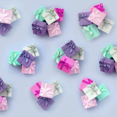 Kurdeleler ile küçük renkli hediye kutuları yığınları bir mor arka plan üzerinde yatıyor