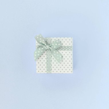 Kurdeleli küçük beyaz hediye kutusu mor bir arka plan üzerinde yatıyor