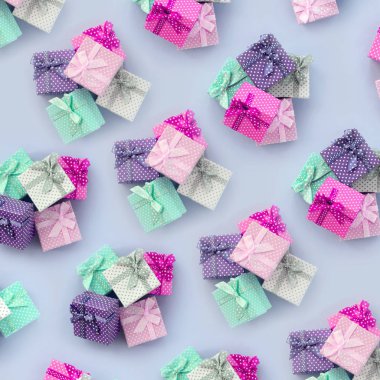 Kurdeleler ile küçük renkli hediye kutuları yığınları bir mor arka plan üzerinde yatıyor