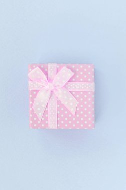 Kurdeleli küçük pembe hediye kutusu mor bir arka plan üzerinde yatıyor