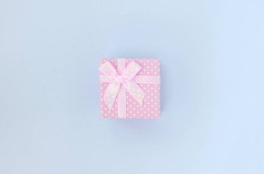 Kurdeleli küçük pembe hediye kutusu mor bir arka plan üzerinde yatıyor