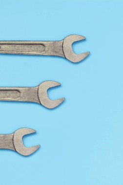 Üç metalik spanners moda pastel mavi renkli kağıt doku arka plan üzerinde yalan
