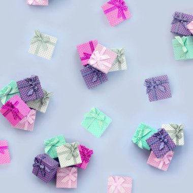 Kurdeleler ile küçük renkli hediye kutuları yığınları bir mor arka plan üzerinde yatıyor