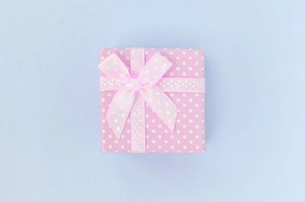 Маленькая розовая коробка подарка с лентой лежит на фиолетовом фоне — стоковое фото