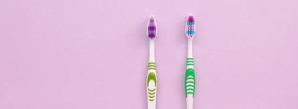 Two toothbrushes lie on a pastel pink background — Stock Photo, Image