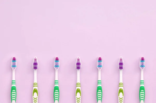 Veel tandenborstels liggen op een pastel roze achtergrond — Stockfoto