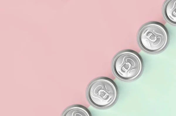 Many metallic beer cans on texture background of fashion pastel turquoise and pink colors