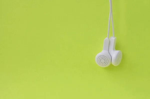 Fones de ouvido modernos brancos pendurados em um fundo brilhante limão — Fotografia de Stock