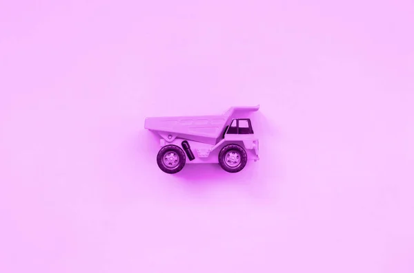 Маленька фіолетова іграшкова вантажівка на текстурі модного пастельного фіолетового кольорового паперу — стокове фото