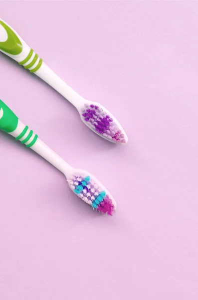 Two toothbrushes lie on a pastel pink background — Stock Photo, Image