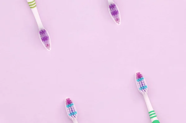 A lot of toothbrushes lie on a pastel pink background — Stock Photo, Image
