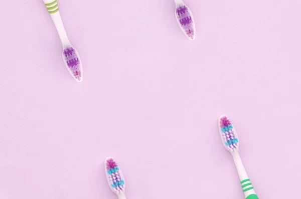 Muitas escovas de dentes estão em um fundo rosa pastel — Fotografia de Stock