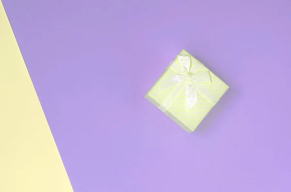 Small yellow gift box lie on texture background of fashion pastel yellow and violet colors — Stock Photo, Image