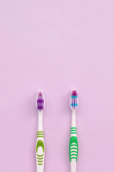 Two toothbrushes lie on a pastel pink background — Stock Photo, Image