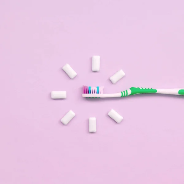 Szczoteczki do zębów i gumy do żucia leżą na pastelowe różowe tło — Zdjęcie stockowe