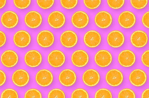明るい紫色の背景にオレンジ色の柑橘系のスライスのパターン — ストック写真