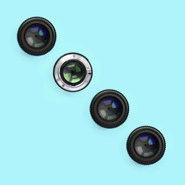 A few camera lenses with a closed aperture lie on texture background of fashion pastel blue color paper — Stock Photo, Image