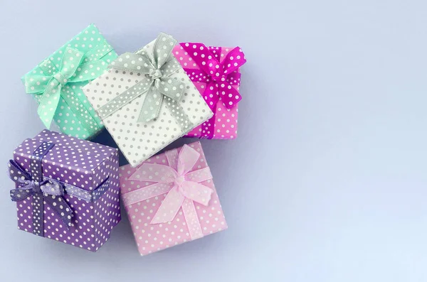 Pile of a small colored gift boxes with ribbons lies on a violet background — Stock Photo, Image