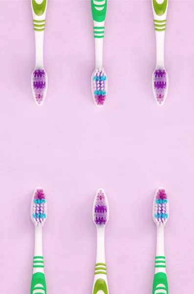 A lot of toothbrushes lie on a pastel pink background — Stock Photo, Image