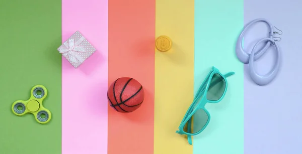 Trendy fashionable pastel composition with earrings, sunglasses, beverage can, basketball ball, gift box and spinner — Stock Photo, Image