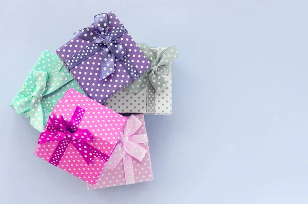 Куча маленьких цветных подарочных коробок с лентами лежит на фиолетовом фоне — стоковое фото